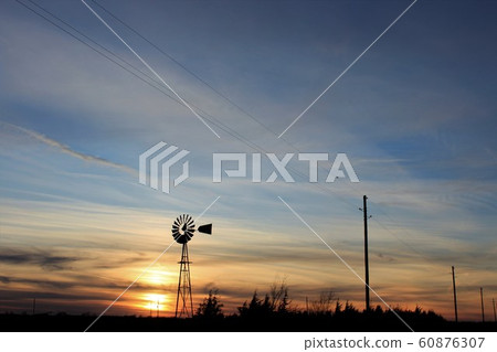 Kansas colorful Sunset with a colorful sky,tree's and a Windmill silhouette. 60876307