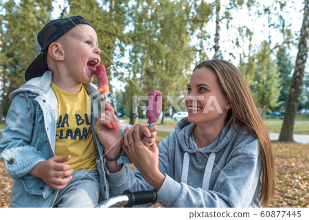 Happy mother son, eat ice cream, play, laugh smile, summer day park autumn, casual clothes, jeans, care and support love happiness on weekend. Rest with parent nature. Emotions of delight pleasure. Happy mother son, eat ice cream, play, laugh smile, summer day park autumn, casual clothes, jeans, care and support love happiness on weekend. Rest with parent nature. Emotions of delight pleasure. 60877445