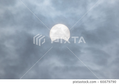 Partial sun eclipse behind clouds Partial sun eclipse behind clouds 60879790