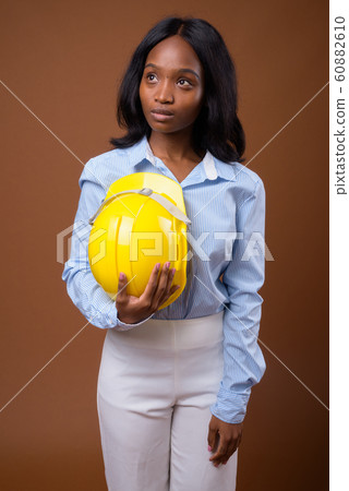 Young beautiful African Zulu businesswoman with hardhat against Young beautiful African Zulu businesswoman with hardhat against 60882610