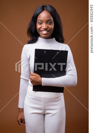 Young beautiful African Zulu businesswoman against brown backgro Young beautiful African Zulu businesswoman against brown backgro 60882845
