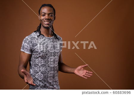 Young handsome African man against brown background 60883696