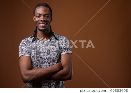 Young handsome African man against brown background 60883698