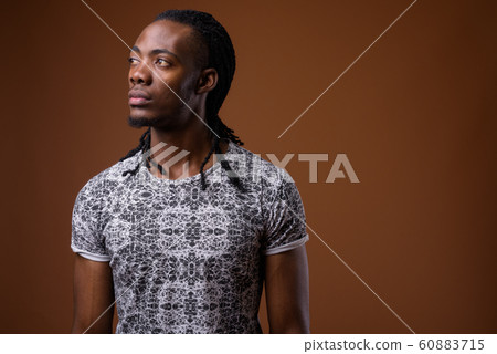 Young handsome African man against brown background Young handsome African man against brown background 60883715