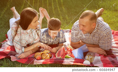 happy family members lie on stomach on red blanket at picnic 60884947