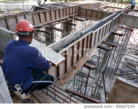 Construction workers fabricating steel reinforcement bar and timber formwork at the construction site. The basic method to create reinforced concrete structure. Construction workers fabricating steel reinforcement bar and timber formwork at the construction site. The basic method to create reinforced concrete structure. 60887239