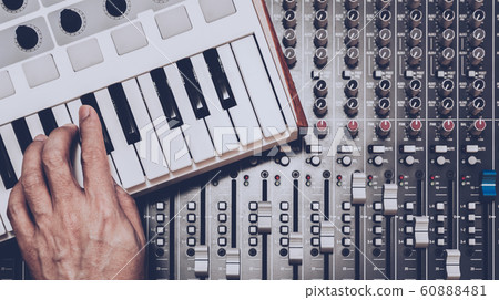 musician hand playing midi keyboard on audio mixing console 60888481