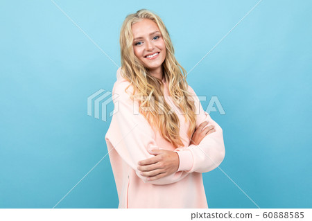 Caucasian woman with blonde hair in pink hoody smiles isolated on blue background 60888585