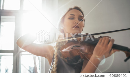 Young Attractive Woman In A Beautiful Dress Is Playing The Violin Young Attractive Woman In A Beautiful Dress Is Playing The Violin 60889491
