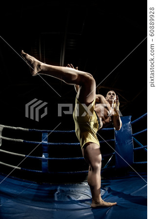 Thai boxer on boxing ring, kicking 60889928