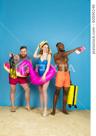 Happy young friends resting on blue studio background Happy young friends resting on blue studio background 60890146