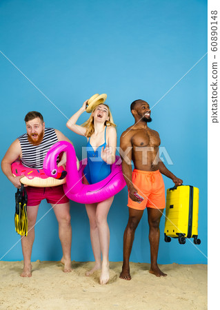 Happy young friends resting on blue studio background 60890148