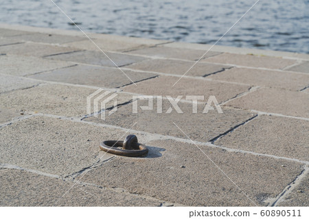Ship mooring ring on the pier close up, water on the background, horizontal image Ship mooring ring on the pier close up, water on the background, horizontal image 60890511
