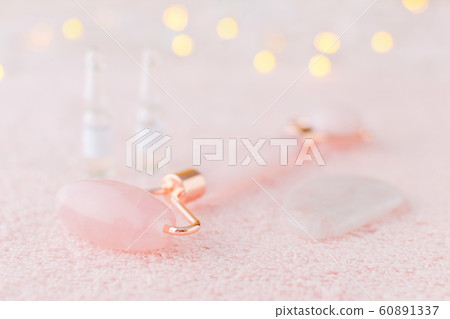 real rose quartz facial roller, gua sha massage stone and face serum in ampoules, selective focus real rose quartz facial roller, gua sha massage stone and face serum in ampoules, selective focus 60891337
