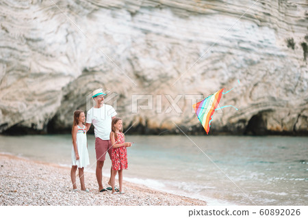 Family flying kite together at tropical white beach Family flying kite together at tropical white beach 60892026