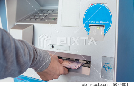 Close up of hand withdraw money in Thai baht currency from bank machine.  Cash out money at an ATM. 60898011