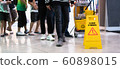 Janitor Cleaning Floor In Front Of Yellow Caution "Cleaning in progress". Cleaning service in public area. 60898015
