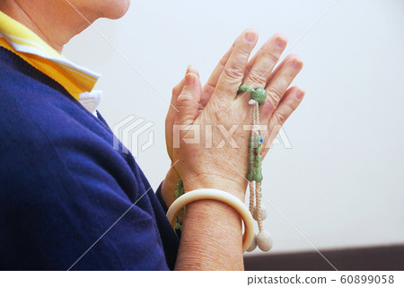 Woman press the hands together at the chest in sign of respect and hold prayer beads on hands for praying Woman press the hands together at the chest in sign of respect and hold prayer beads on hands for praying 60899058