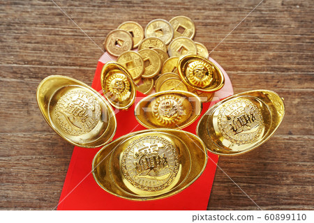 Topview gold bars and background coins spread out from red envelope with old wood background, chinese new year concept. Topview gold bars and background coins spread out from red envelope with old wood background, chinese new year concept. 60899110