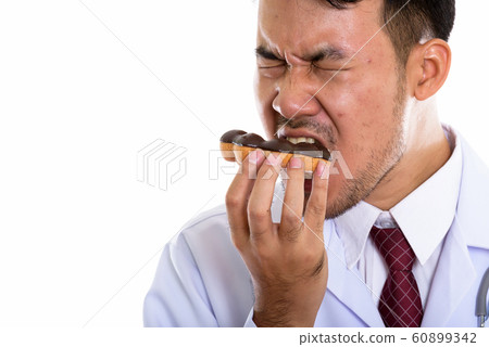 Close up of young Asian man doctor eating donut with eyes closed 60899342