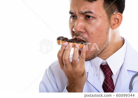Close up of young Asian man doctor eating donut and thinking 60899344