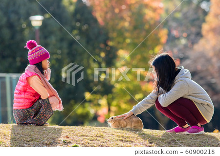 Children sisters playing with rabbit in winter park Children sisters playing with rabbit in winter park 60900218