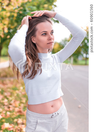 Beautiful girl in autumn in park. Resting weekend in park. Emotions of comfort are pleasure and enjoyment. Autumn day portrait, warm casual wear white blouse, background trees leaves. Beautiful girl in autumn in park. Resting weekend in park. Emotions of comfort are pleasure and enjoyment. Autumn day portrait, warm casual wear white blouse, background trees leaves. 60901560
