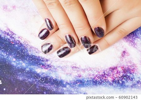 manicure stylish concept: woman fingers with nails purple glitter on nails like cosmos, universe background manicure stylish concept: woman fingers with nails purple glitter on nails like cosmos, universe background 60902143
