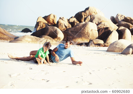 happy family on beach playing, father with son walking sea coast, rocks behind smiling taking vacation 60902680