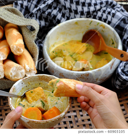 People eating delicious yellow vegan curry dish bowl with bread for breakfast 60903105
