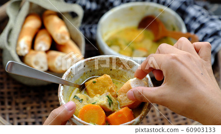 People eating delicious yellow vegan curry dish bowl with bread for breakfast People eating delicious yellow vegan curry dish bowl with bread for breakfast 60903133