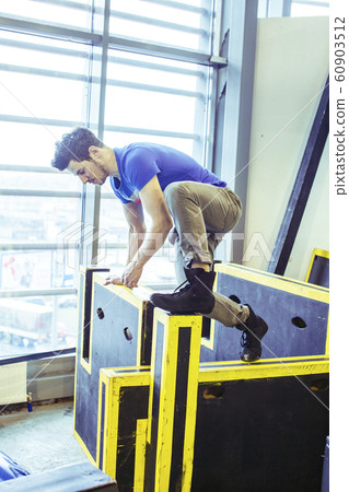 young handsome man doing parkour in gym inside, lifestyle sport people concept young handsome man doing parkour in gym inside, lifestyle sport people concept 60903512