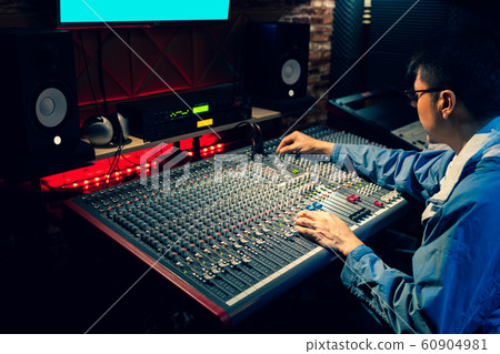 asian professional producer working on audio mixing console in recording, broadcasting studio asian professional producer working on audio mixing console in recording, broadcasting studio 60904981
