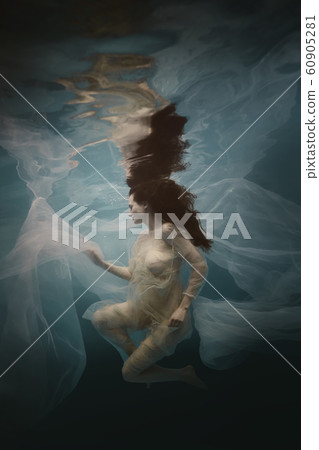 Girl in a white dress with a cloth swims underwater 60905281