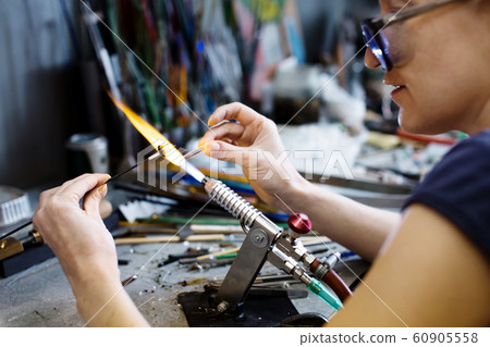 Woman artist making glass jewelry in her workshop 60905558