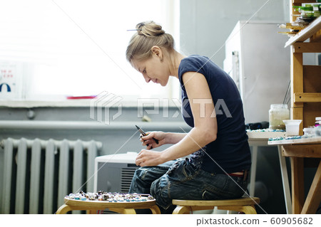 Woman artist making glass jewelry in her worksho 60905682