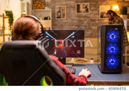 Back view of female gamer playing on powerful computer PC late at night in the living room 60906858