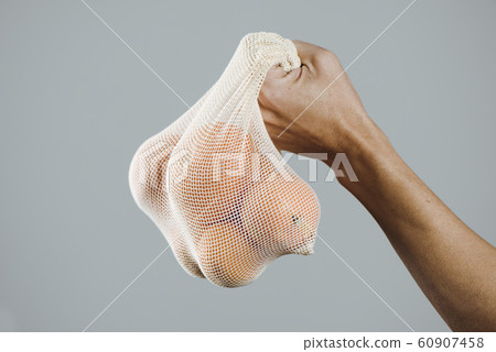 man and reusable mesh bag with oranges. 60907458