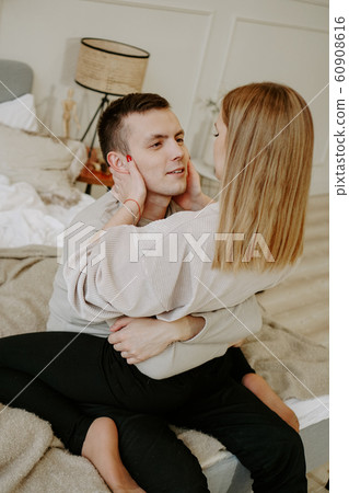 Close-up portrait of a beautiful young couple hugs in bed at home Close-up portrait of a beautiful young couple hugs in bed at home 60908616