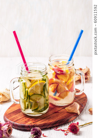 Two mugs of infused detox diet refreshing waters - first with cucumber and lemon, second with lemon and peach 60911592