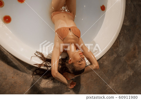 Sexy young woman with perfect body in a bath with milk and circles of grapefruit 60911980