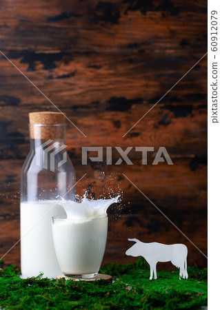 Bottle and glass of milk with splash with grass and silhouete of caw Bottle and glass of milk with splash with grass and silhouete of caw 60912079