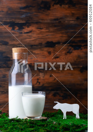 Bottle and glass of milk on grass and silhouete of caw Bottle and glass of milk on grass and silhouete of caw 60912084