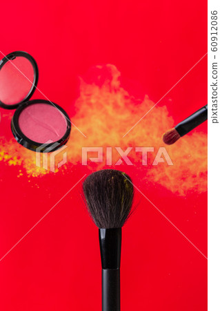cosmetic brush and sprayed cloud of cosmetics on a red concept 60912086