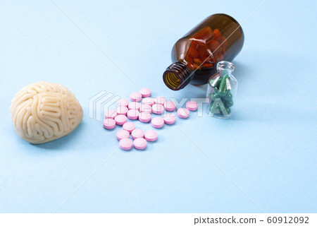 Brain on a blue background with white pills in a glass bottle. Some pills for the brain. Symbolical for medicines, psychopharmaceuticals, nootropics and other medicines. Medicine. Brain treatment 60912092