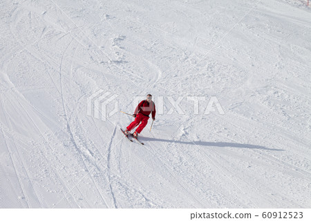 Skier on snowy sunlit ski slope at winter 60912523
