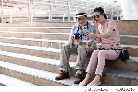 Senior Asian couples sit on the stairs while 60920210