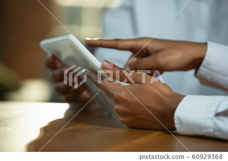 Close up of african-american human's hands using tablet on wooden table 60929368