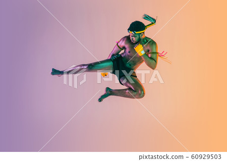 Muay thai. Young man exercising thai boxing on gradient background 60929503