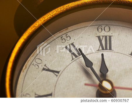 Golden vintage alarm clock showing five to twelve 60930767